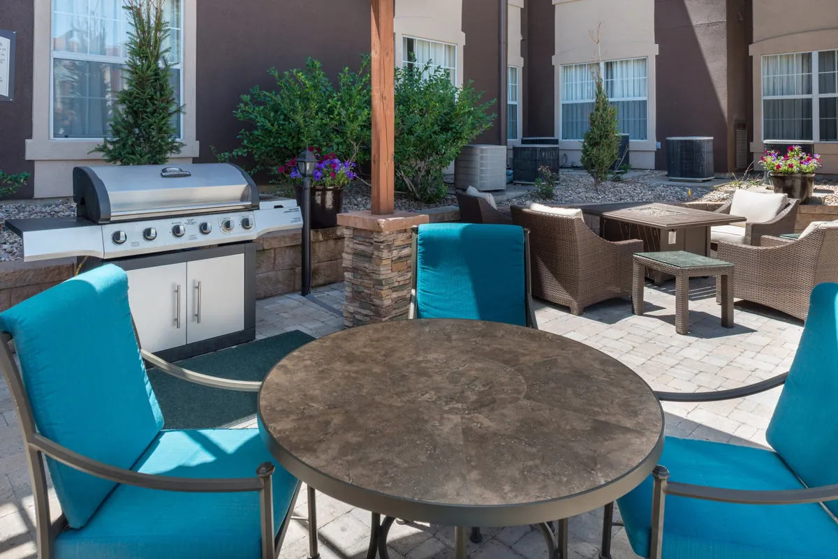 An inviting outdoor area featuring a grill, ample seating around tables, and lush landscaping. The setting suggests opportunities for barbecuing, relaxed outdoor dining, and social gatherings, with a family-friendly atmosphere perfect for enjoying sunny days after exploring nearby attractions.