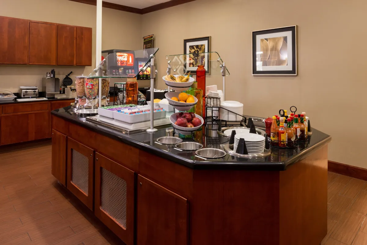 A welcoming breakfast bar setup with a colorful fruit display and a well-stocked beverage station. The arrangement invites guests to socialize and enjoy a fresh meal in a communal and lively environment.